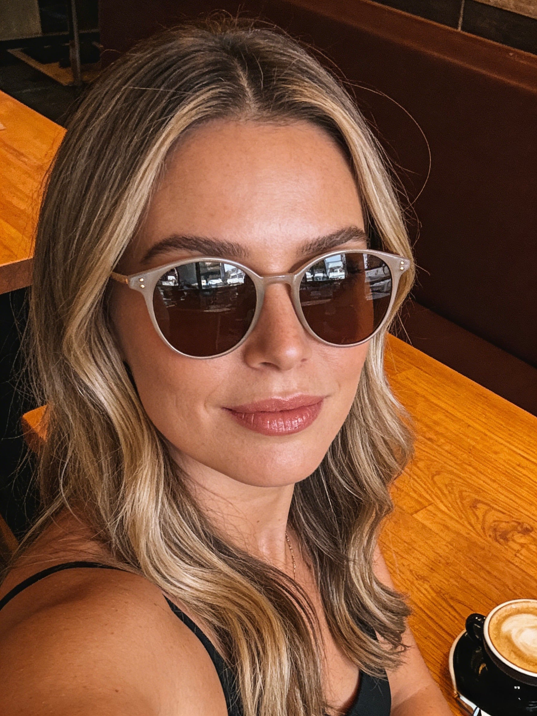 Woman wearing sunglasses with a blurred background.Classic round unisex beige color sunglasses | polarised lenses, 100% UV protection, stylish trendy fashion