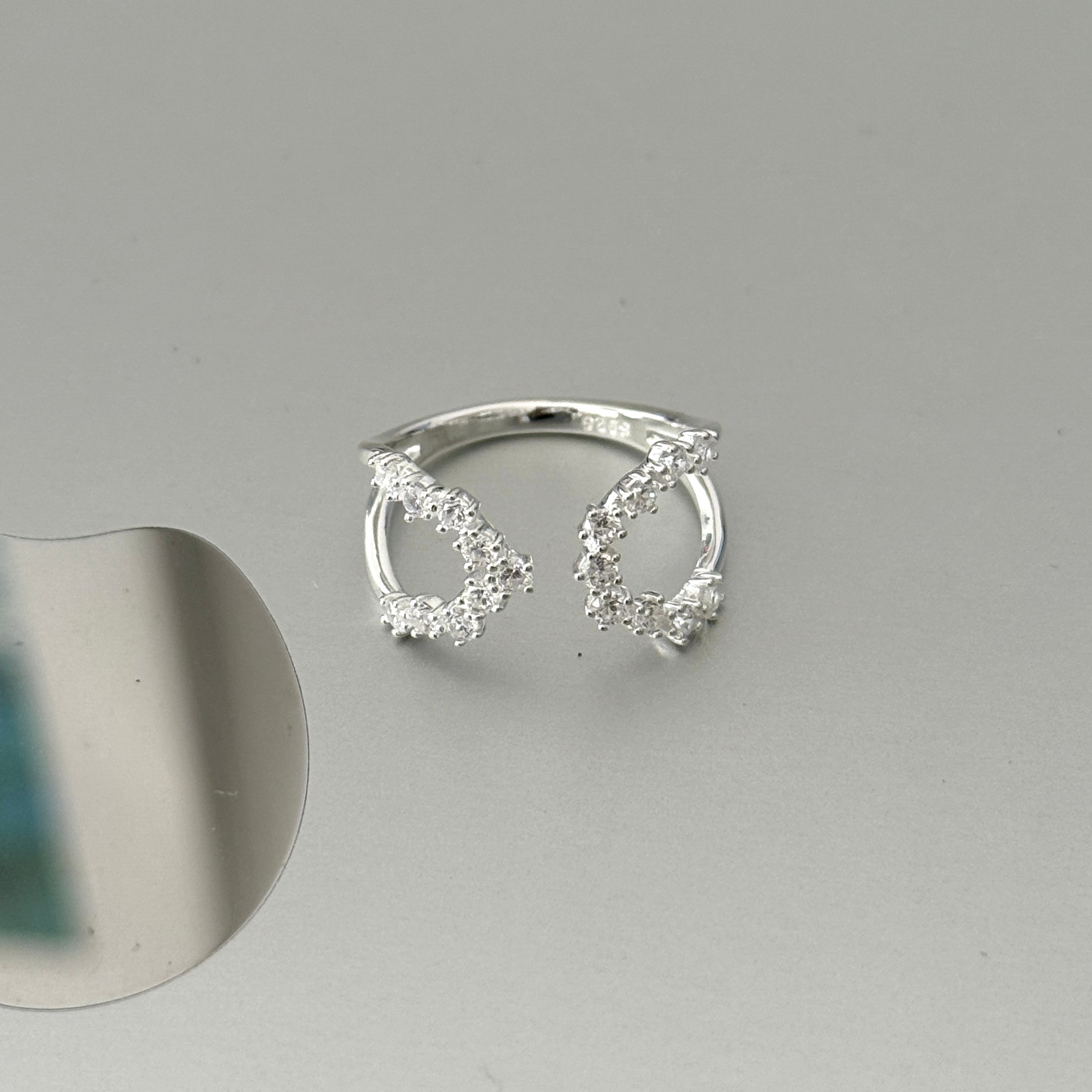 A minimalist adjustable ring in sterling silver, showcasing sparkling zirconia stone in an open, fluid design for a comfortable fit.