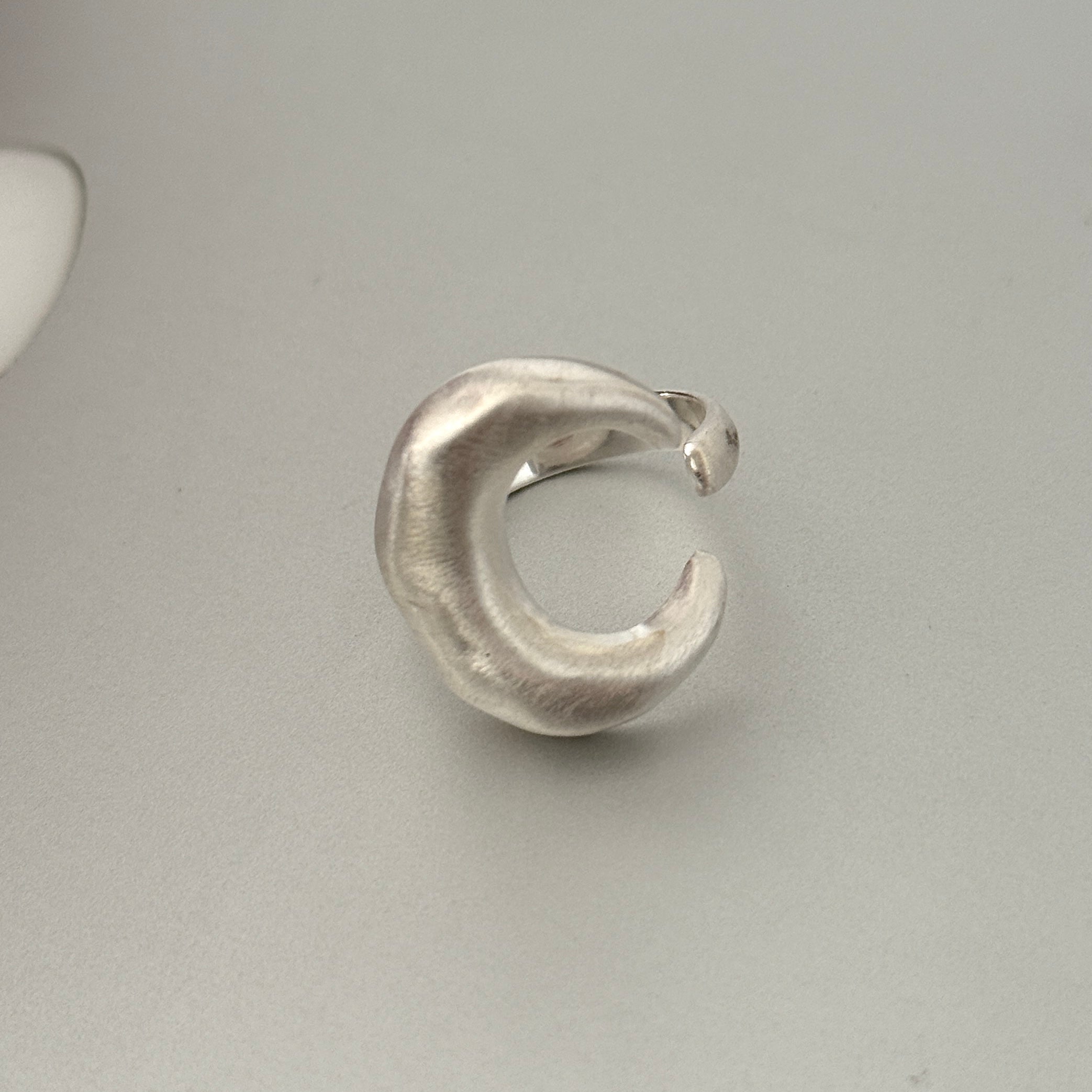 A chunky sterling silver ring featuring a bold, full moon motif with a matte finish. This substantial unisex jewelry piece has an organic and modern sculptural form.