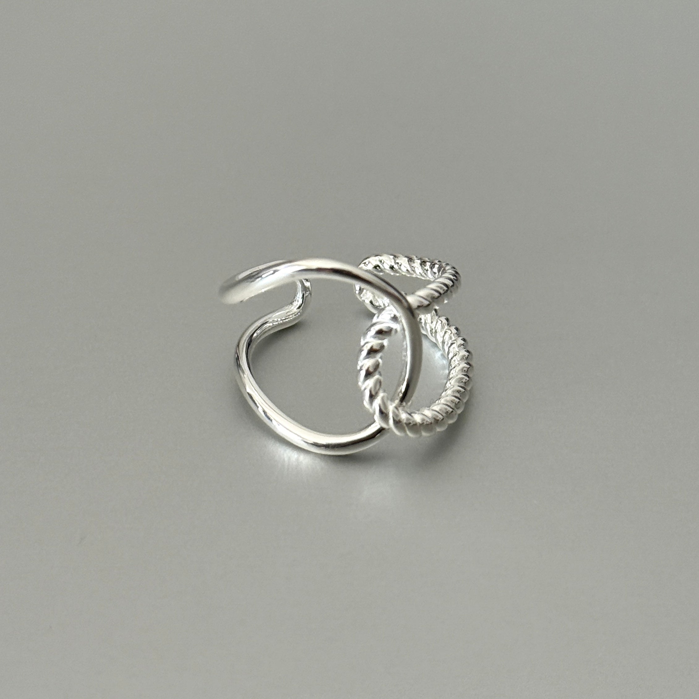Close-up detail of the Amara ring, highlighting the textural contrast between the smooth polished silver and the intricate braided rope pattern.