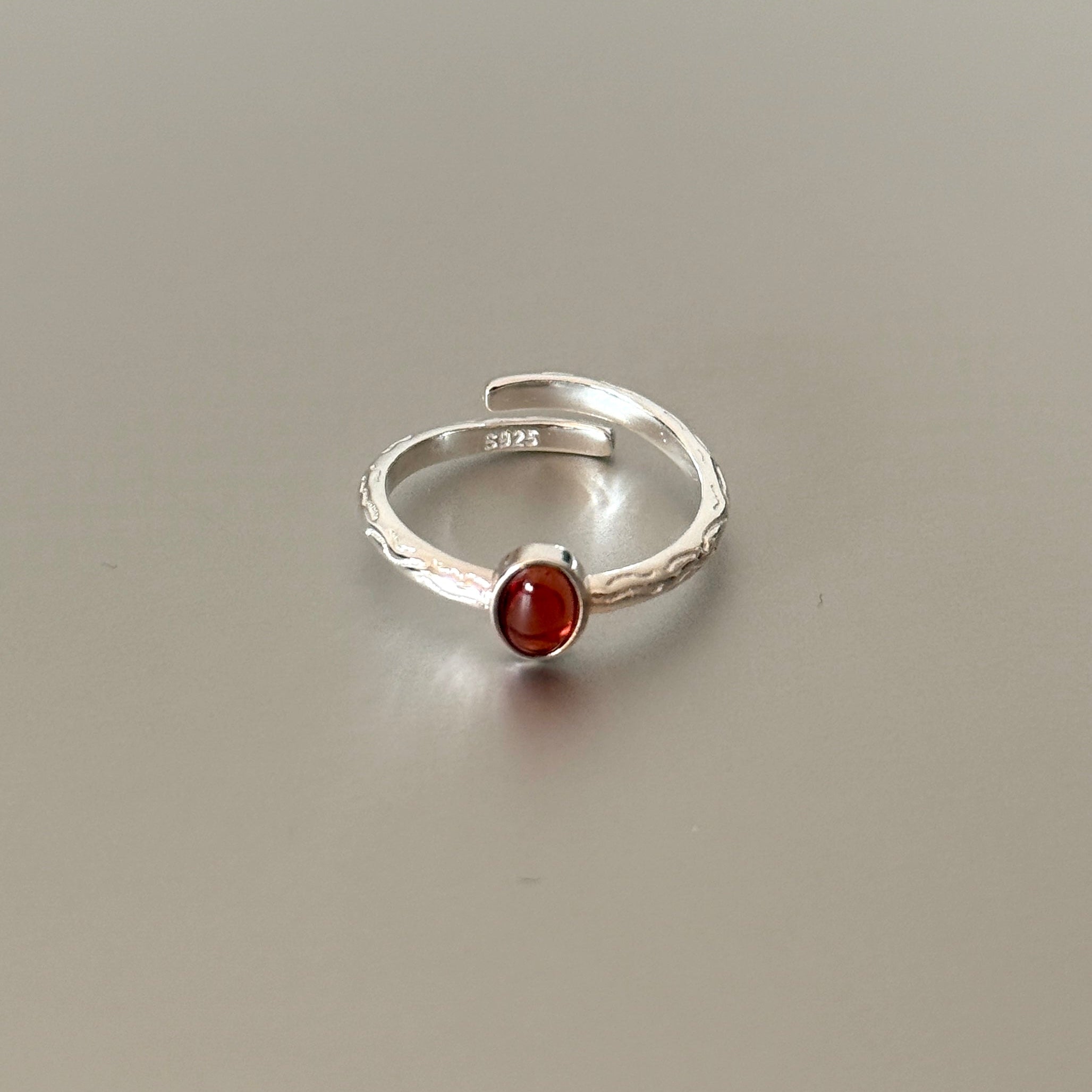 Close-up detail of the Sable ring, highlighting the rough branch texture and the deep red color of the natural garnet gemstone.