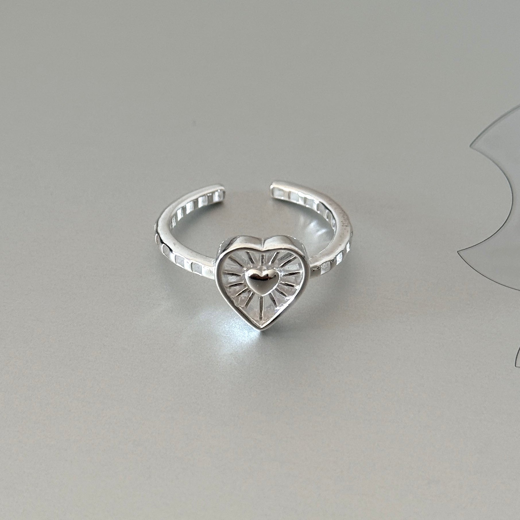 Close-up of the Thalia ring, highlighting the small heart centered within a sunburst textured open heart.
