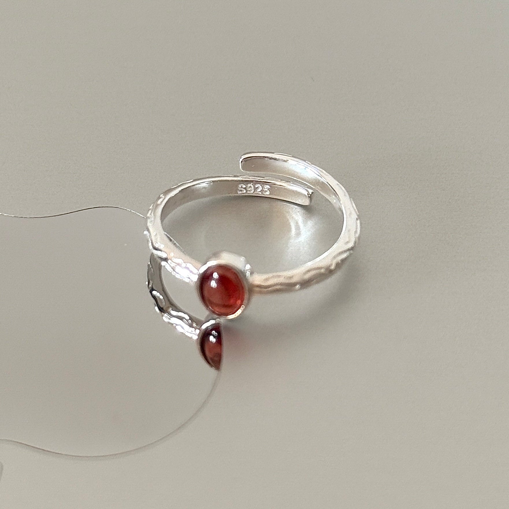 Close-up detail of the Sable ring, highlighting the rough branch texture and the deep red color of the natural garnet gemstone.