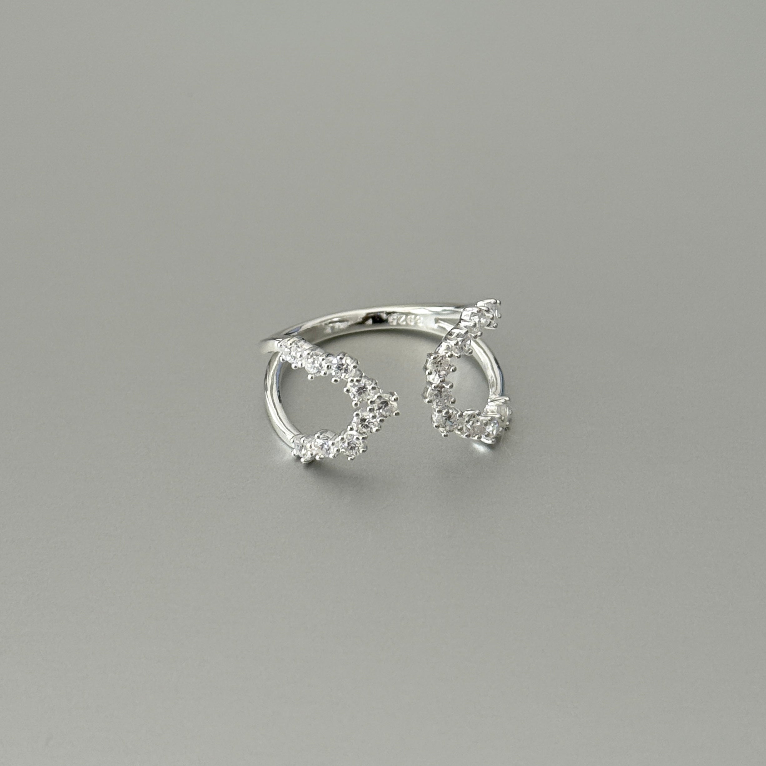 A minimalist adjustable ring in sterling silver, showcasing sparkling zirconia stone in an open, fluid design for a comfortable fit.