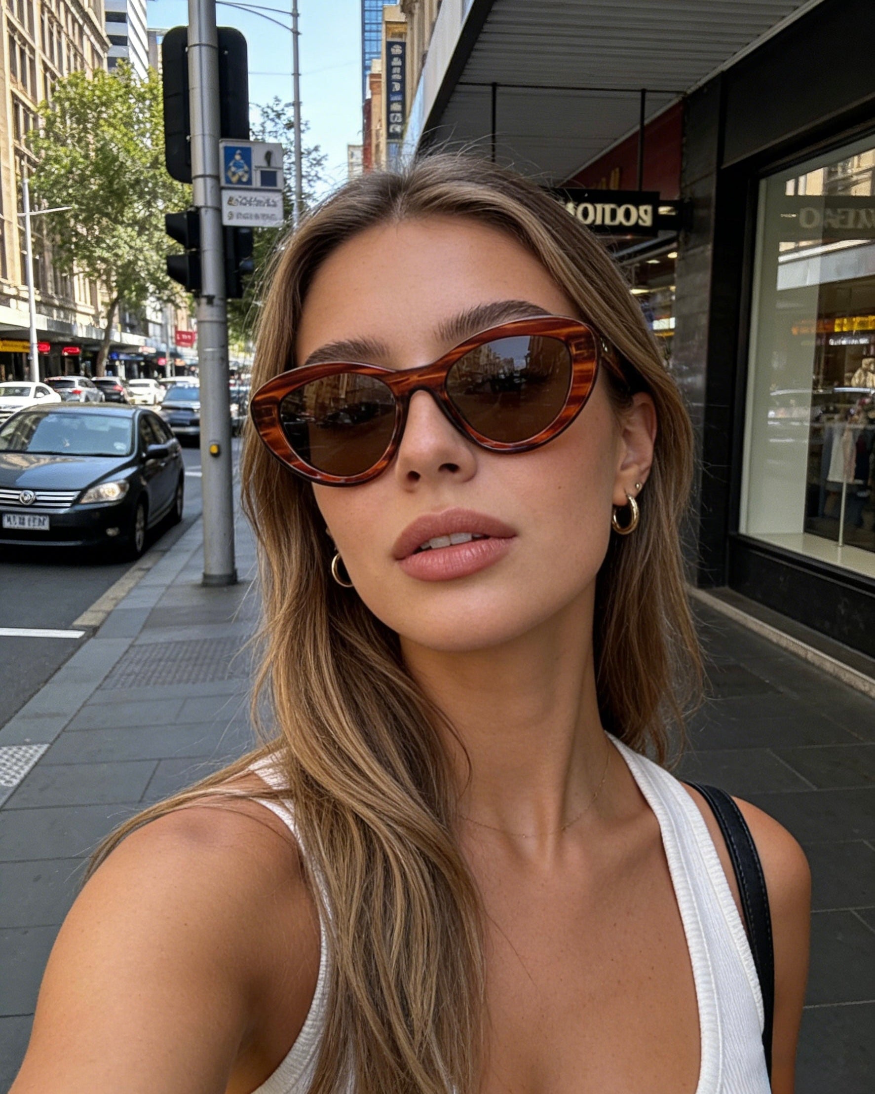 Bold black cat-eye sunglasses with thick frames, polarized lenses with UV protection, retro aesthetic eyewear for women. Brown wood grain pattern cat-eye sunglasses with tea-tinted polarized lenses and UV protection, vintage organic style eyewear.