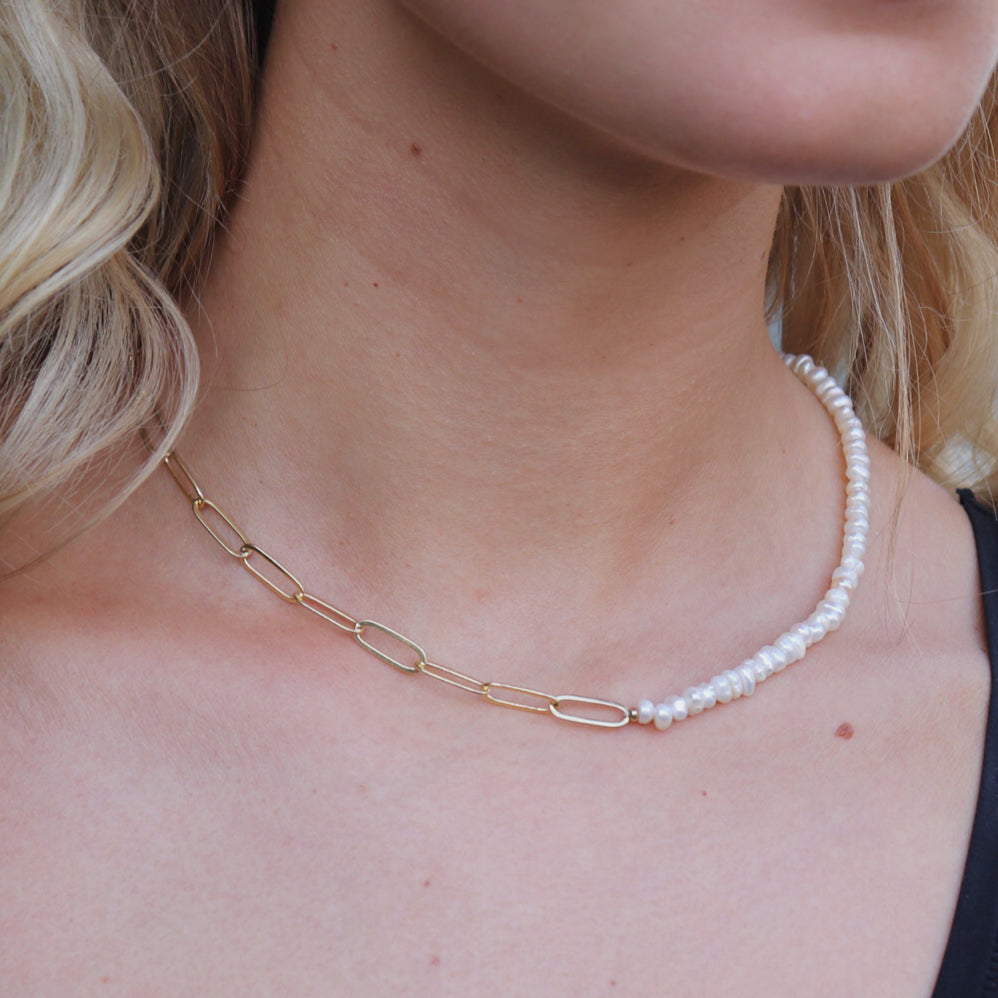 Close-up of Hazel necklace's asymmetric design, showcasing the contrast between polished gold links and lustrous pearls.