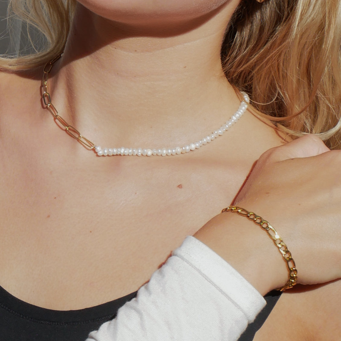 Hazel asymmetric choker necklace on neck, featuring an 18K gold plated oval link chain half and a freshwater pearl strand half.