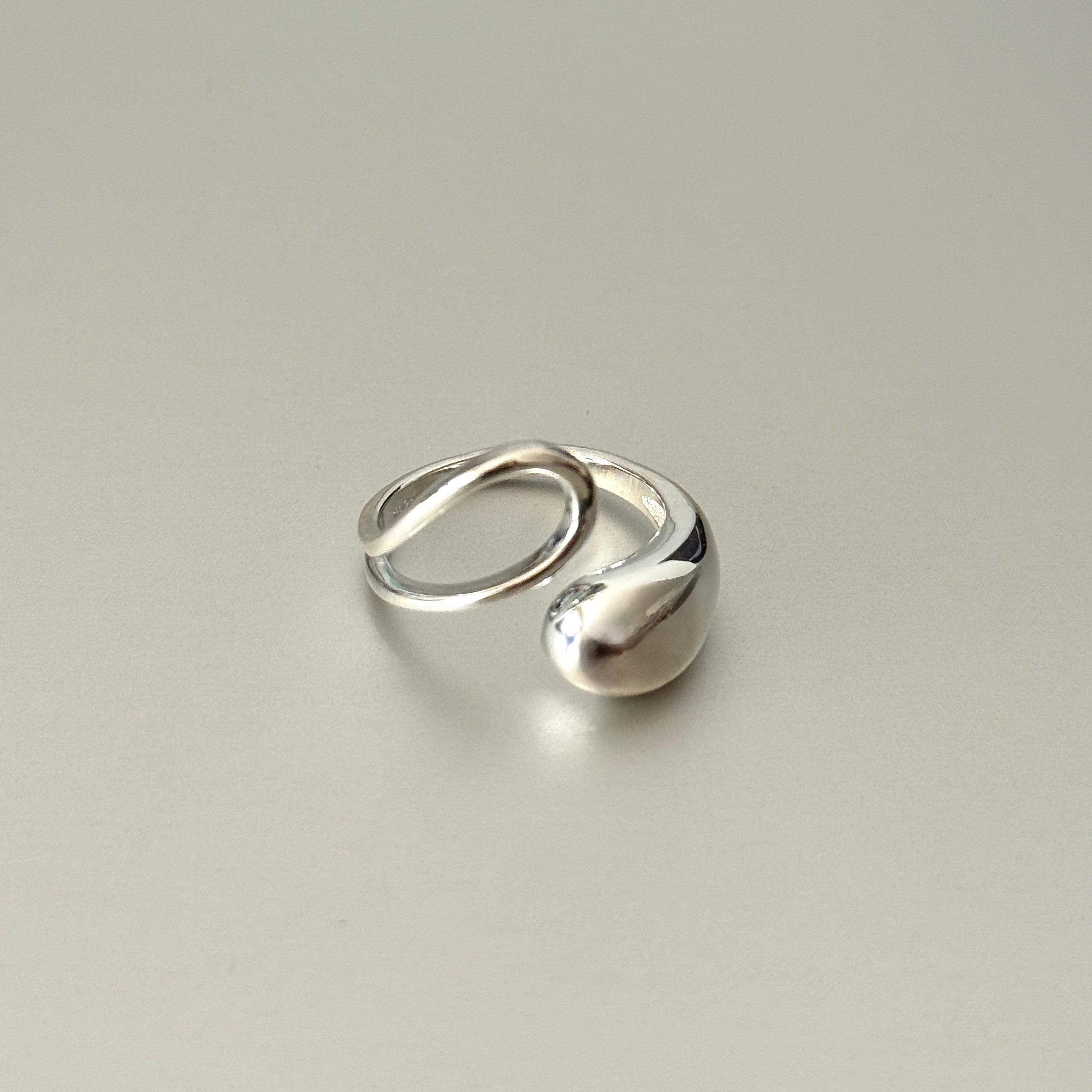 Sleek minimalist 925 sterling silver statement ring with fluid curved design – polished metallic luxury jewelry for modern sophisticated style.