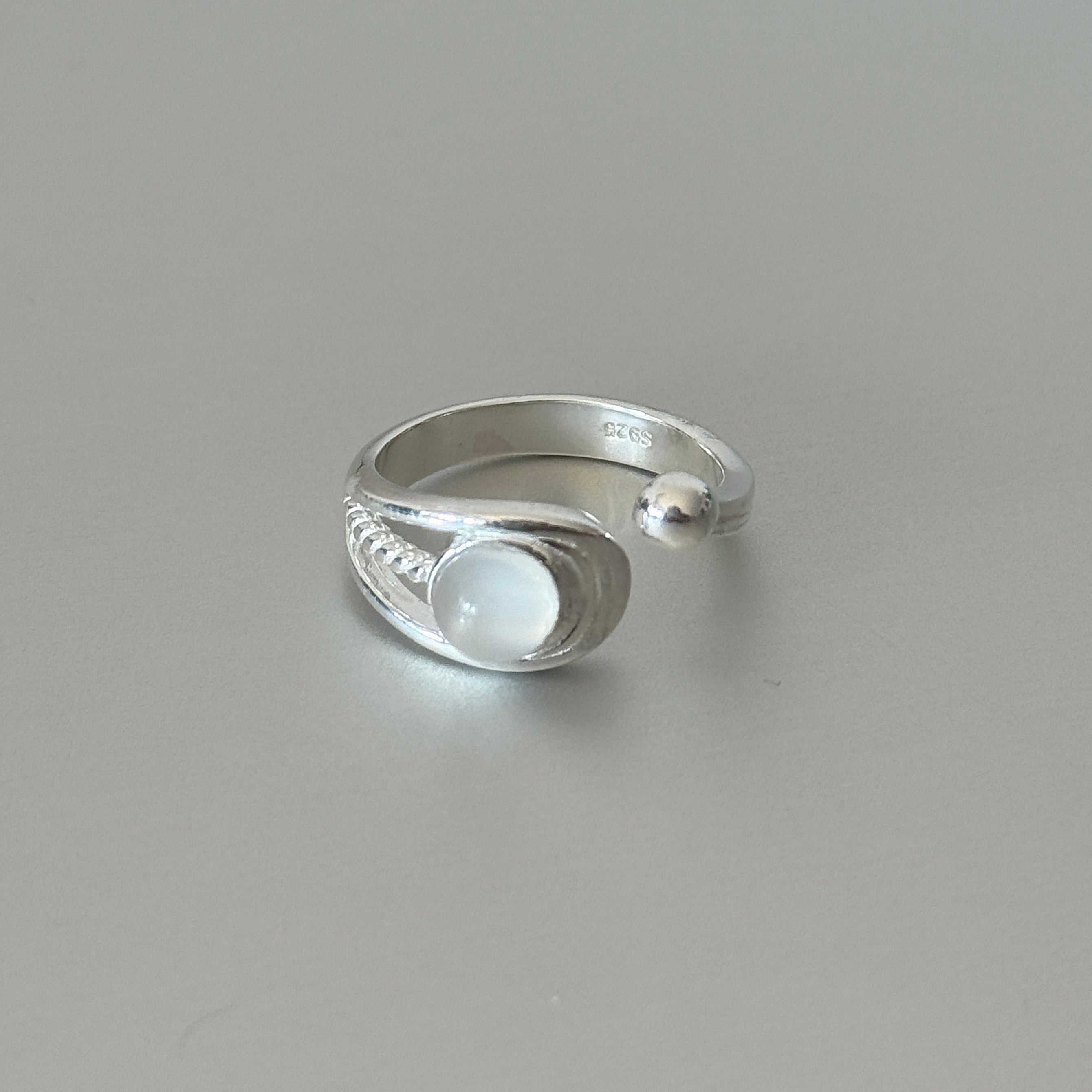 The Tamsin moonstone ring worn alone, showcasing its braided sterling silver band and ethereal gemstone on an open adjustable design.