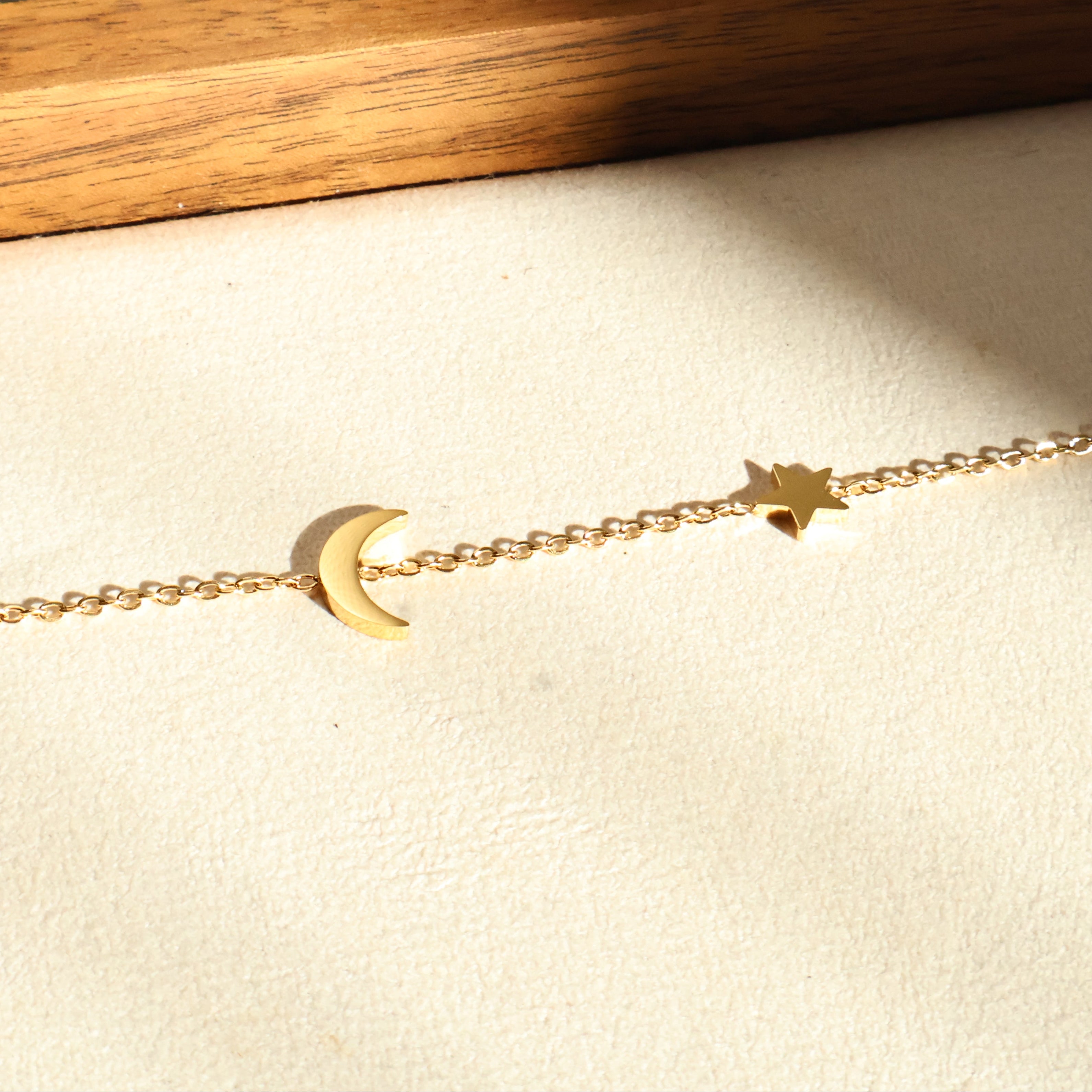 Thea bracelet worn solo on wrist, showcasing star and moon charms on a delicate gold chain