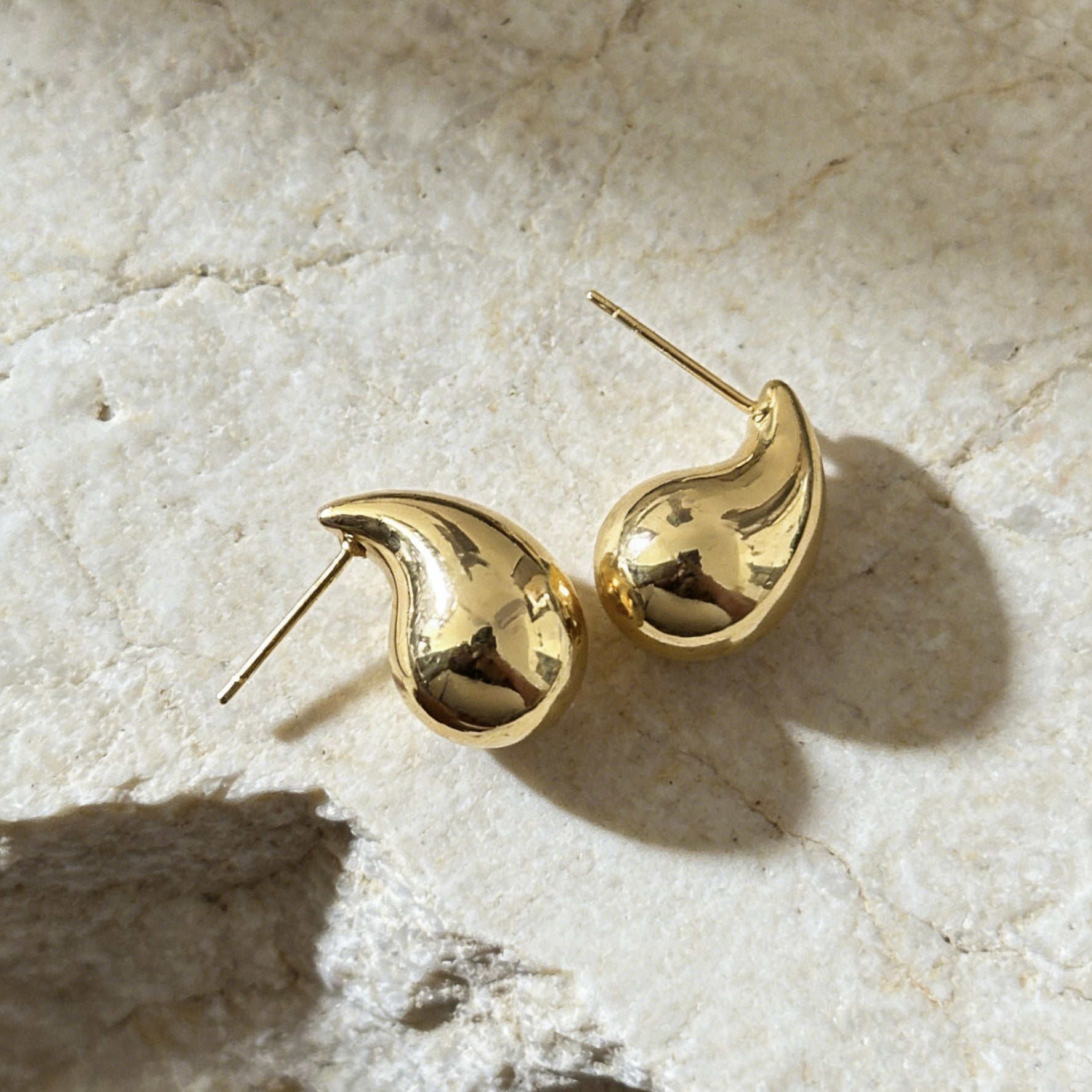 18K gold plated teardrop-shaped stud earrings with sterling silver posts,  minimalist jewelry photography.  chunky bean-style earrings offer a bold yet minimalist statement.